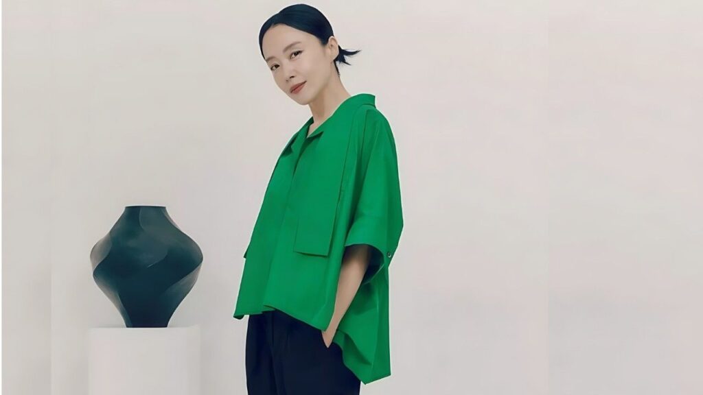 Jeon Do-yeon beside a dark sculptural vase on pedestal in a minimalist studio.