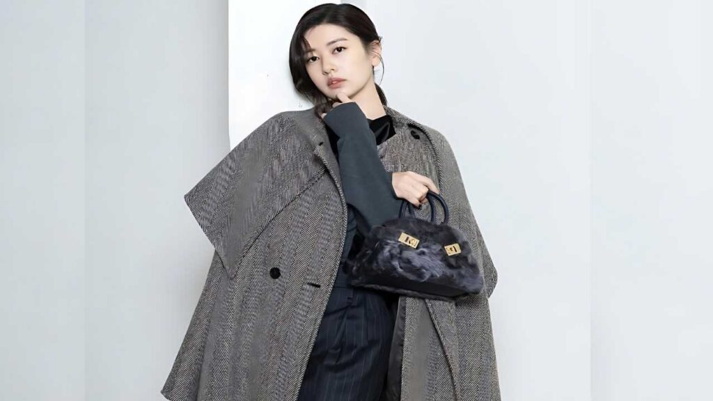 Jung So-min in an oversized gray herringbone coat, holding a black faux-fur handbag with gold hardware.