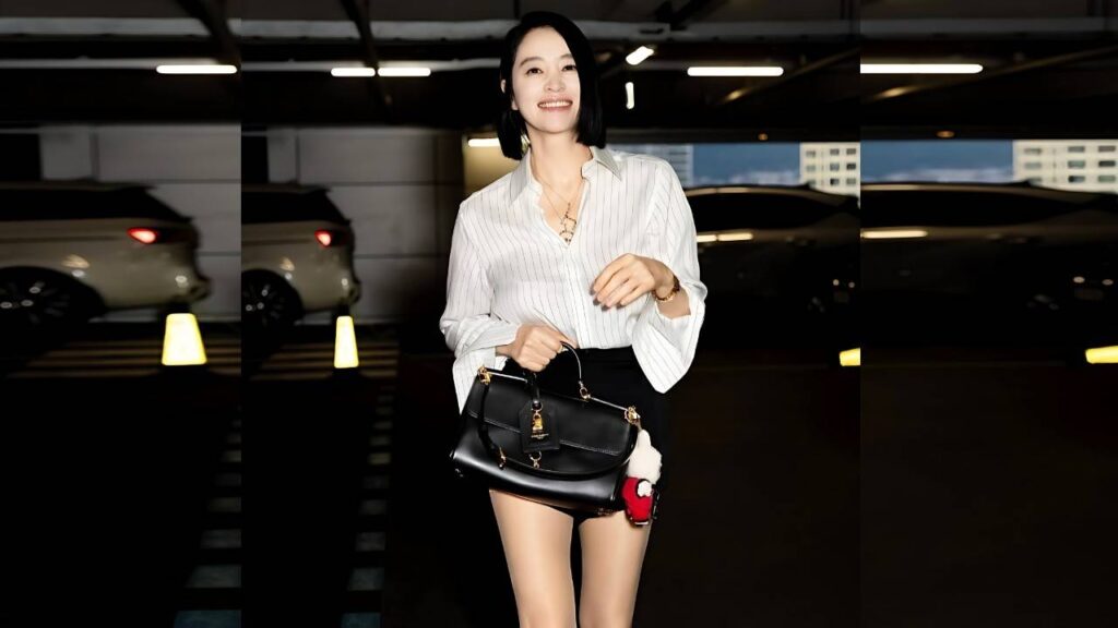 Kim Hye-soo with short black hair in a striped blouse and black mini skirt carries a black handbag in a dim parking garage.