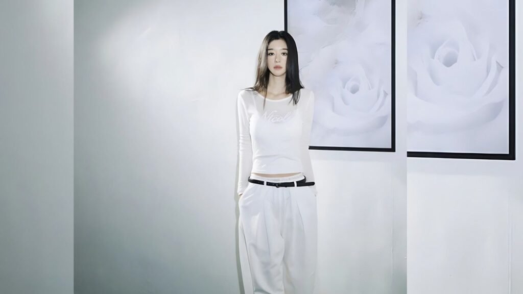Seo Yea-ji in a white outfit stands against a pale wall, with framed white rose art beside her.