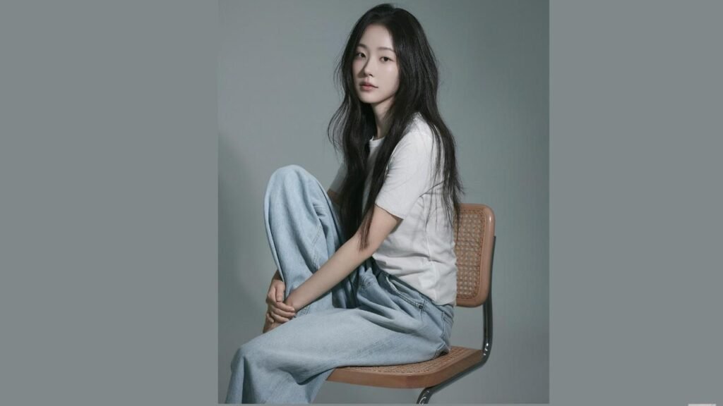 Chae Won-bin (채원빈) with long dark hair sits sideways on chair, wearing a white T-shirt and light blue jeans against a gray backdrop.