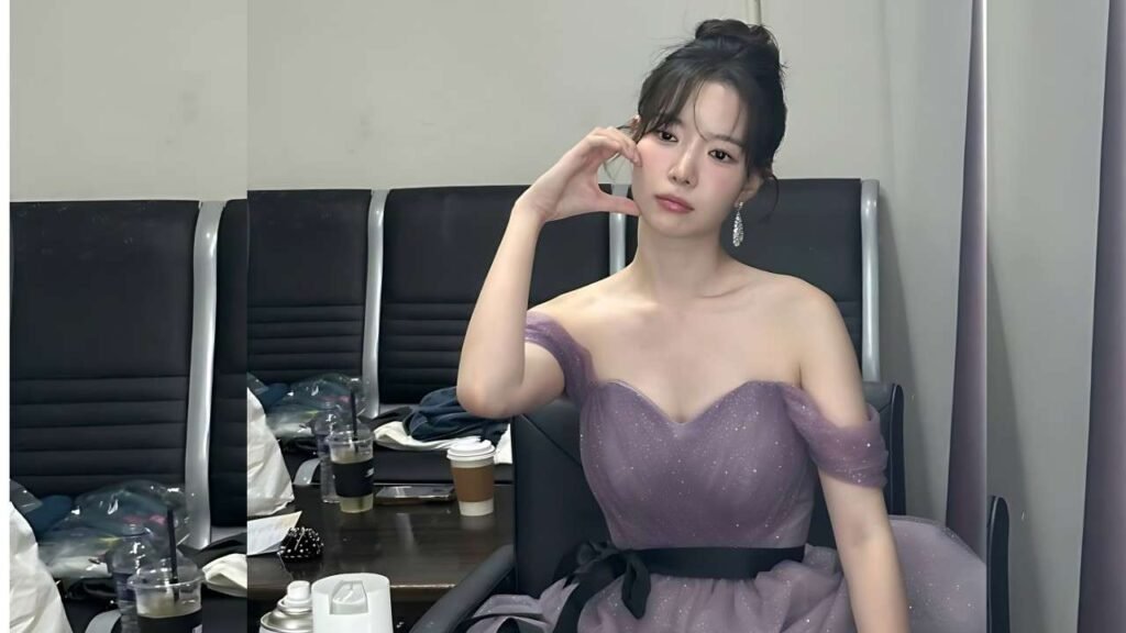 Ha Seung-ri in a lavender off-shoulder gown poses in a dressing room, one hand near her face, among black chairs and drinks.