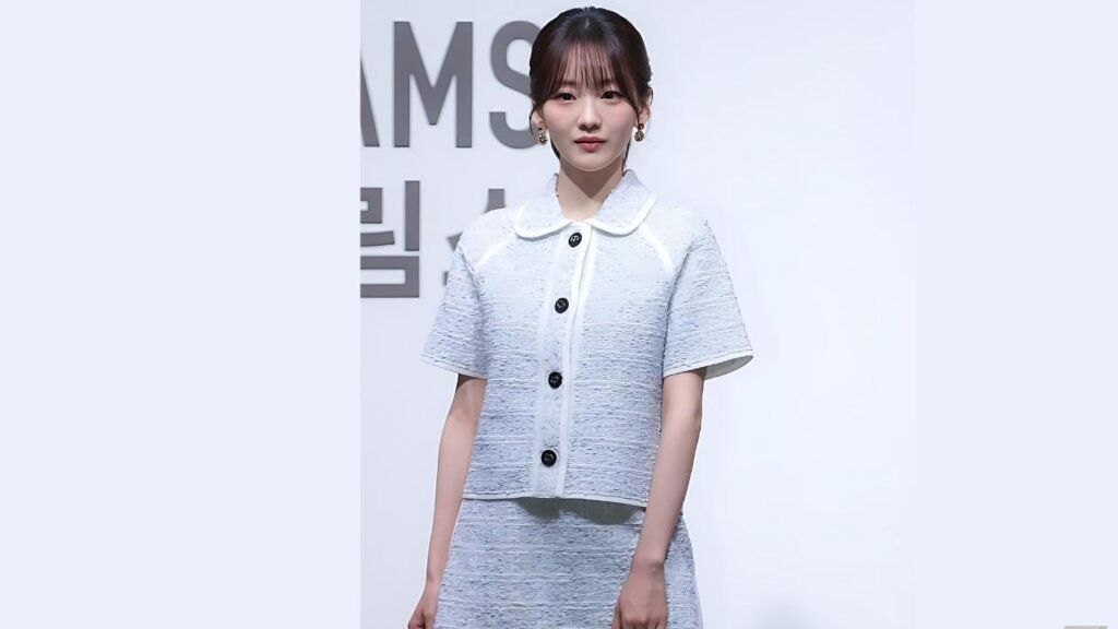 Hyun Young with a pale blue cropped jacket and matching skirt, white collar and black buttons, posing before backdrop.