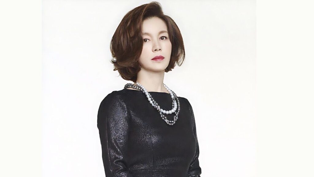 Im Ye-jin (임예진) with a short auburn bob, wearing a black textured dress and layered pearl necklaces, against a pale backdrop.