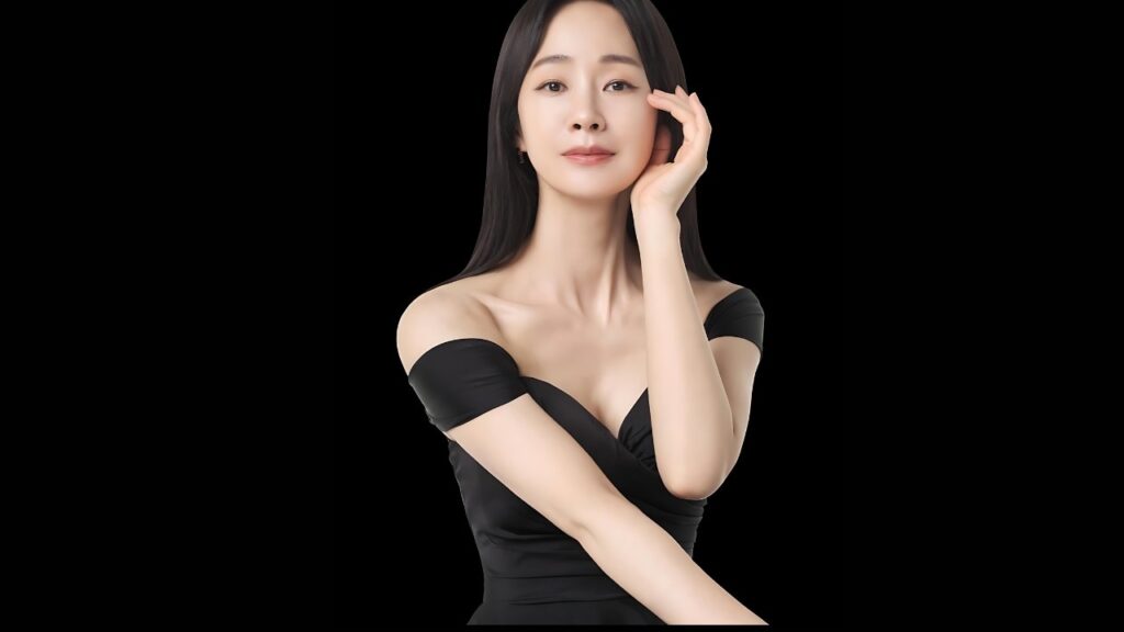 Myung Se-bin in a black off-shoulder dress, one arm across her chest, hand near her cheek against a black background.