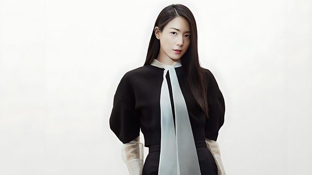 Ryu Hyo-young (류효영) with long dark hair poses in a black dress with puffed sleeves, white cuffs, and a pale blue neck scarf.