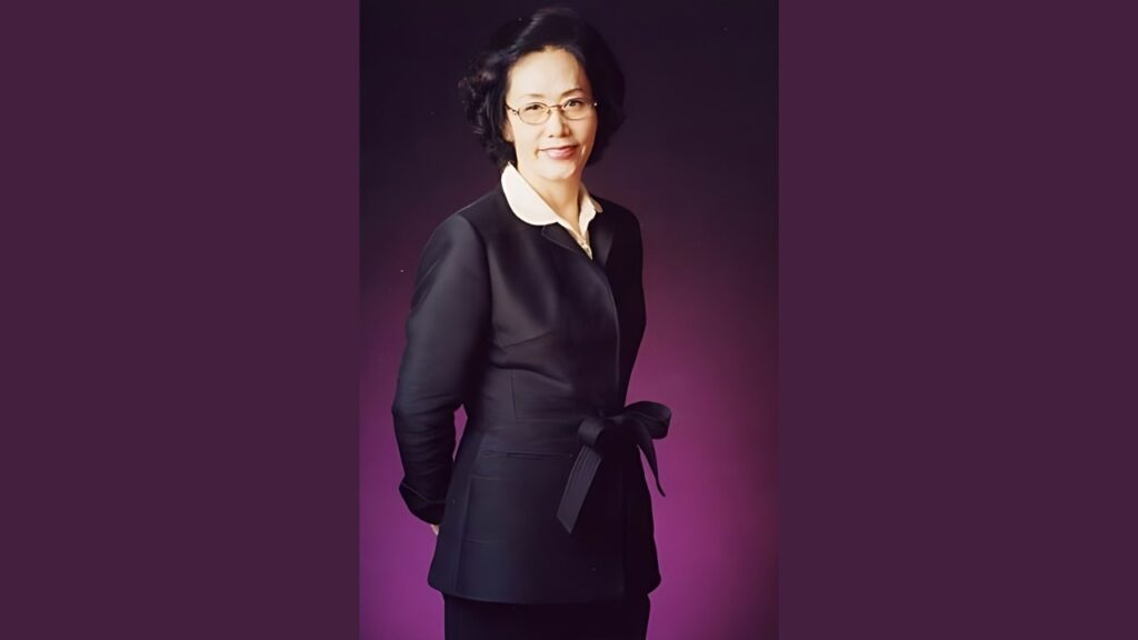 Yeo Woon-kye (여운계) in a black belted blazer with a white collar and glasses, posed before a pink purple gradient backdrop.